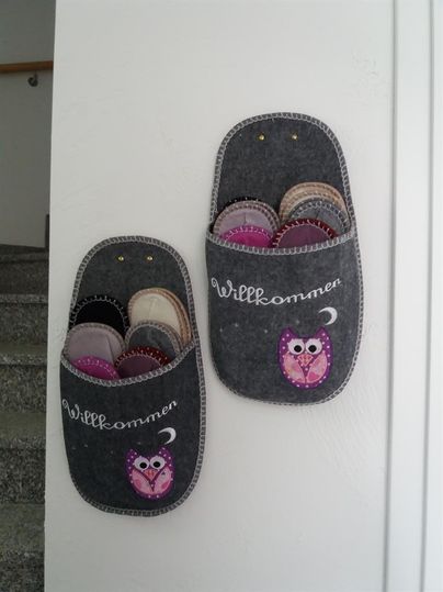 Two gray felt holders with the inscription "Welcome" hang on the wall. They are filled with colorful slippers and display a cute owl.