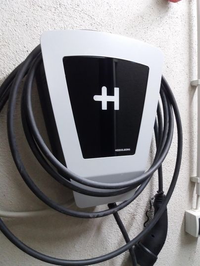 A modern charging station for electric vehicles mounted on a wall. Cables are neatly coiled and ready for use.