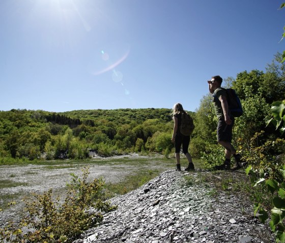 Two hikers on a slate hill, surrounded by green countryside and a bright blue sky, enjoy the view., &copy; Laura Rinneburger
