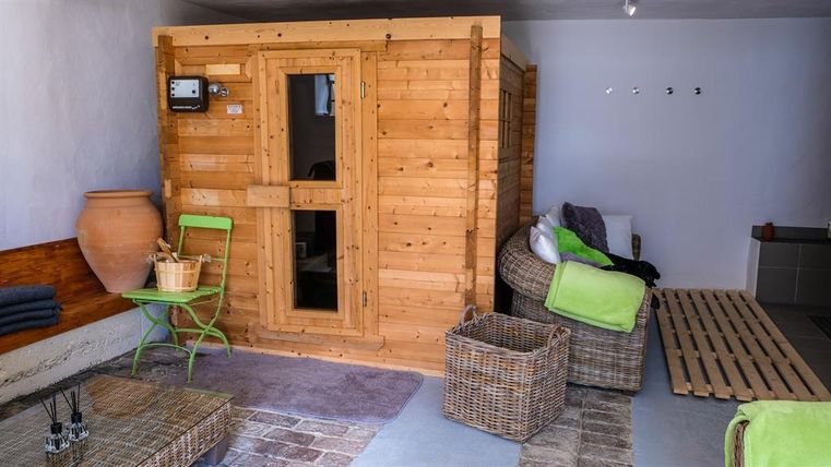 A cozy sauna area with a wooden sauna and comfortable furniture. The atmosphere is relaxed and inviting.