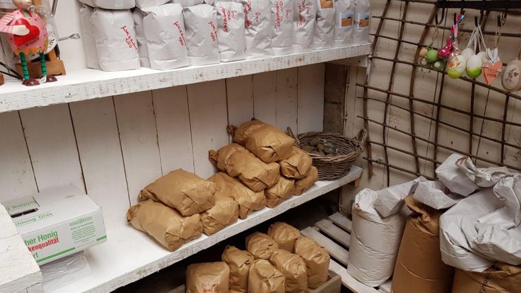 A wooden shelf with several paper bags and small packages. The packages are different colors and are neatly standing next to each other.