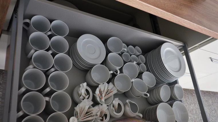 An organized kitchen drawer with cups, plates, and saucers. The dishware is neatly arranged and well sorted.