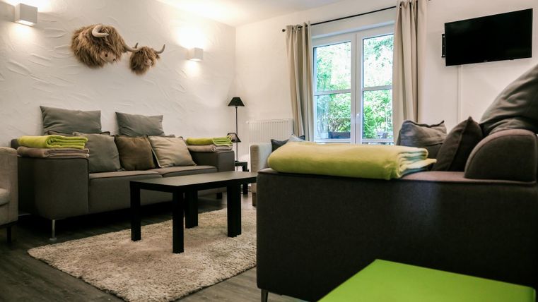 A modern living room with comfortable sofas and a low table. Bright colors and large windows create a pleasant atmosphere.