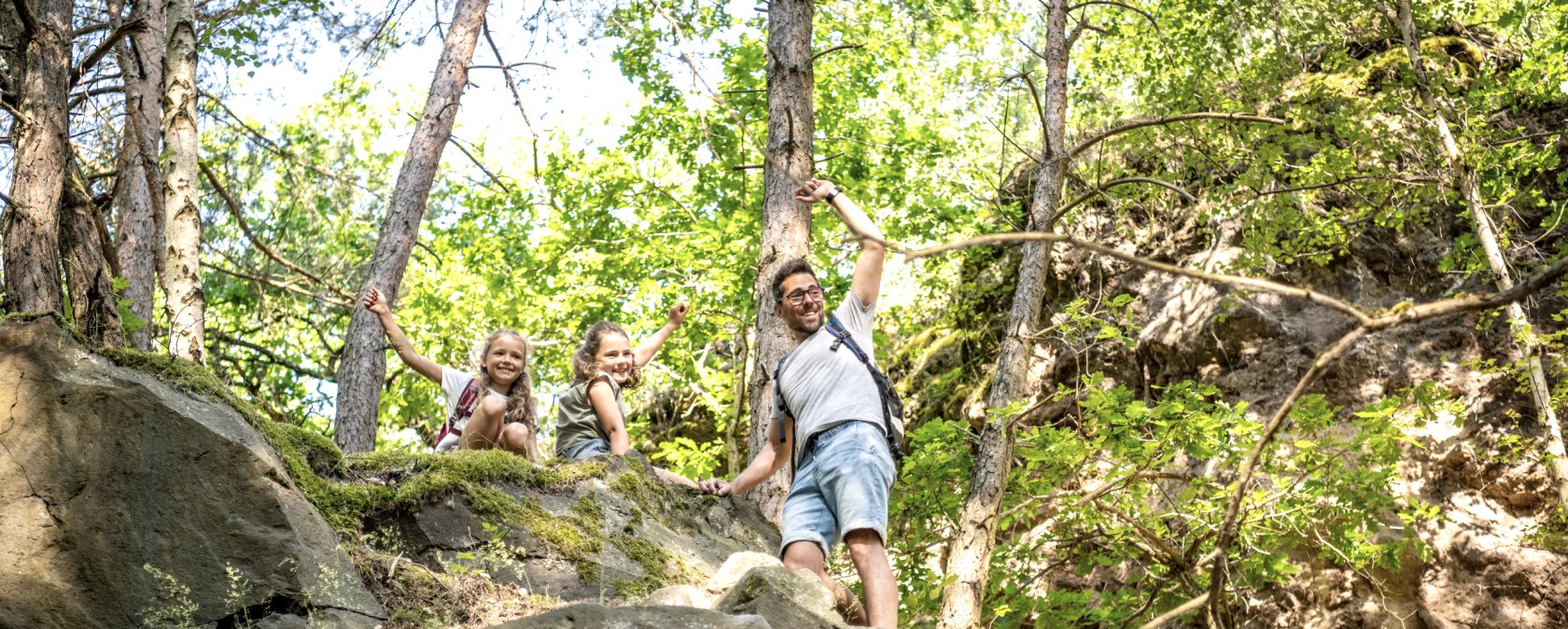 Eine Familie mit zwei Kindern wandert fr&ouml;hlich auf einem felsigen Waldpfad. Sie genie&szlig;en die Natur und das sonnige Wetter., &copy; Eifel Tourismus GmbH, Dominik Ketz