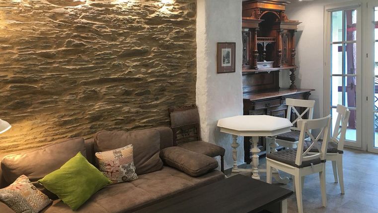 Ein Wohnzimmer mit einem bequemen Sofa und einer Steinwand. Im Hintergrund steht ein eleganter Tisch und Stühle.