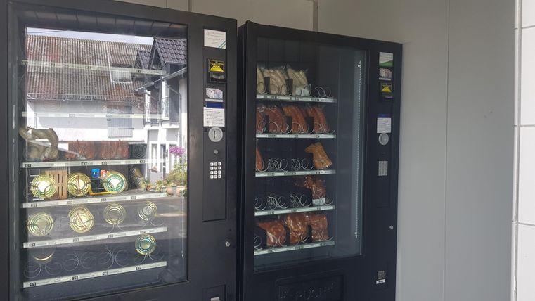 Zwei Verkaufsautomaten stehen nebeneinander. Sie sind mit verschiedenen Snacks und Getränken gefüllt.
