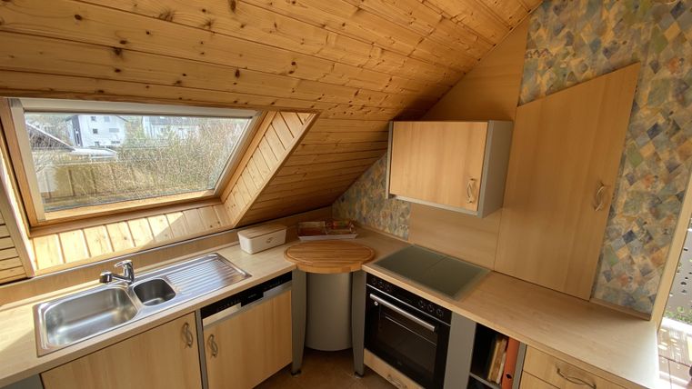 Eine gemütliche Küche mit Holzdecken und modernen Geräten. Sie verfügt über ein Fenster, das viel Licht hineinlässt.