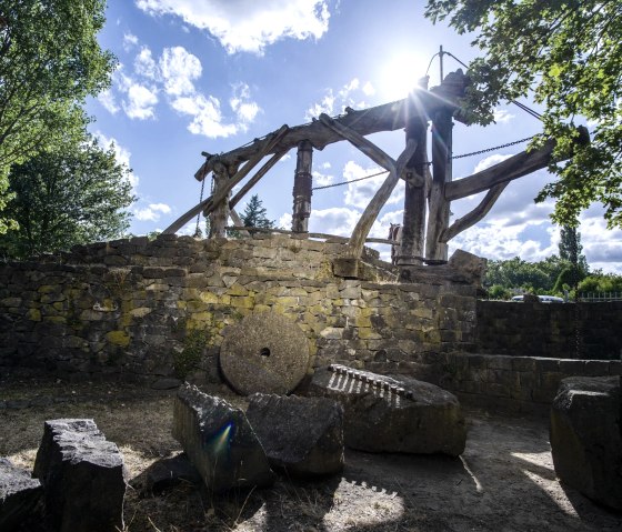 Moulin historique en pierre avec une construction en bois et des meules, entour&eacute; d'arbres et d'un ciel ensoleill&eacute;. Le d&eacute;cor semble calme et idyllique., &copy; Klaus-Peter Kappest/Vulkanregion Laacher See