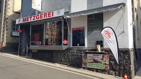 A butcher shop with an open sales area and a decorative stand. Outside, there is an advertisement sign and a banner.